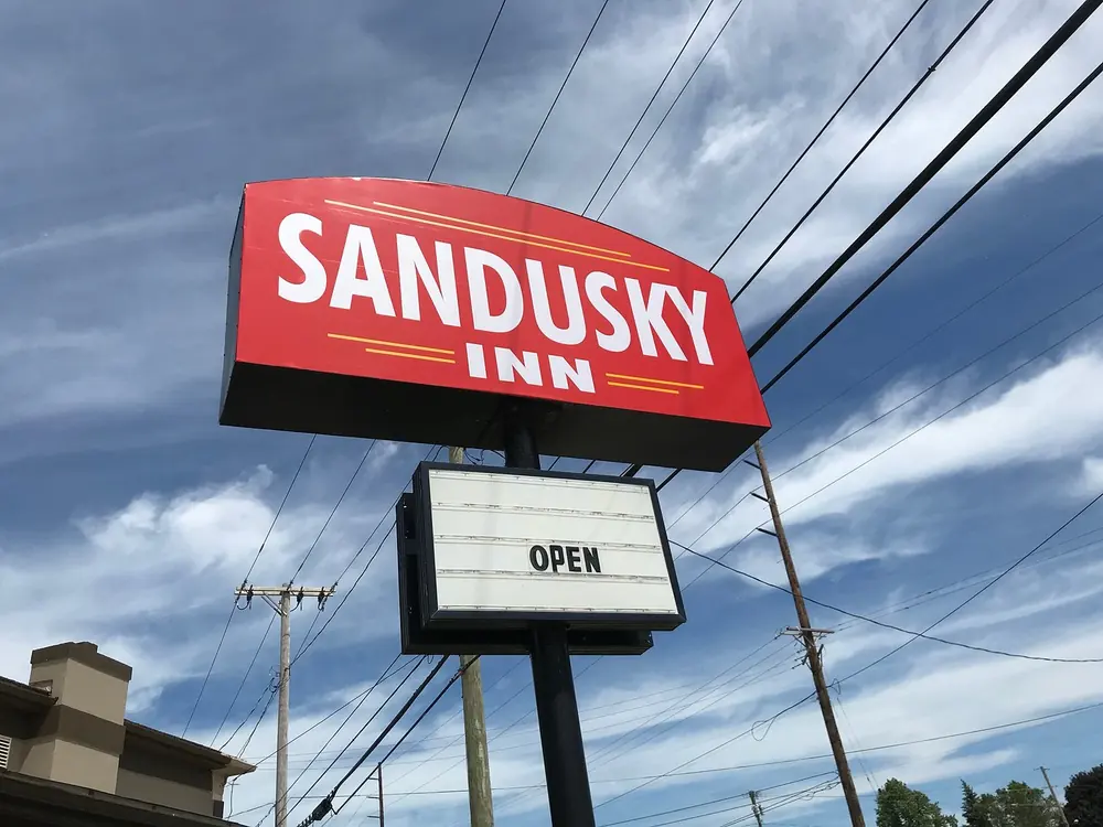 Red Sandusky Inn roadside sign with an open vacancy board against a blue sky